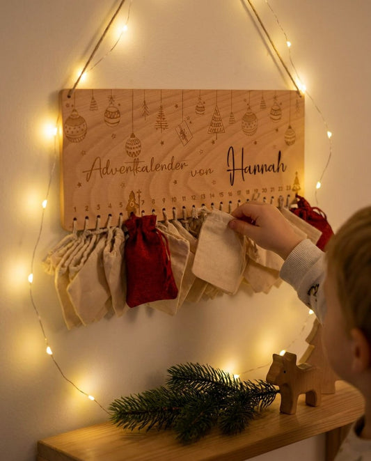 Kinderhand öffnet ein Säckchen am personalisierten Adventkalender