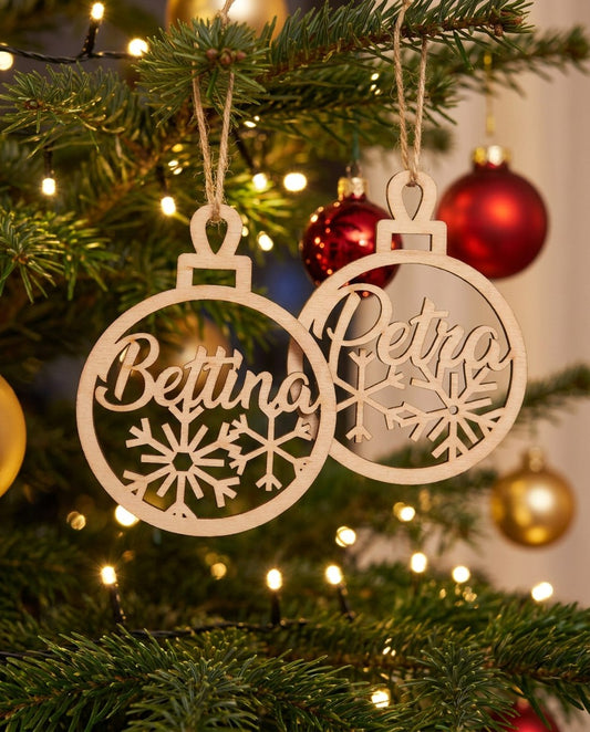 Personalisierte Christbaumkugeln aus Holz mit Namen am beleuchteten Christbaum