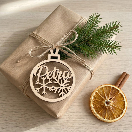 Christbaumkugel aus Holz als Geschenkanhänger an einem Paket in Kraftpapier